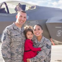 Alex Sawin in her Air Force uniform standing beside her husband and holding her young daughter