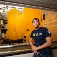 Image of University of Michigan PAVE Team member, Dominic Petersen, standing in front of a block M.