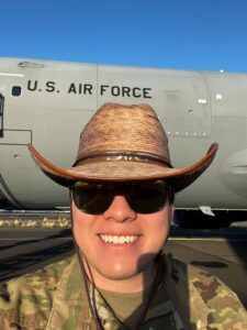 MAn in a hat, uniform, and sunglasses standing in fron of a U.S. Air Force Plane