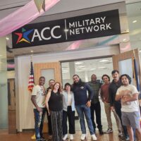 Group of people standing under a banner that reads "ACC Military Network"
