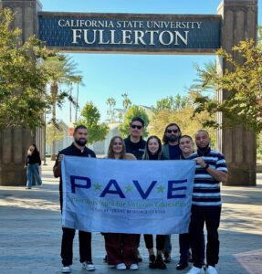 7 people standing under the CSUF sign and holding a PAVE banner