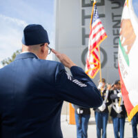 Person in military uniform saluting the national and state flag