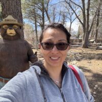 Figure taking a selfie in front of a statue of Smokey the Bear