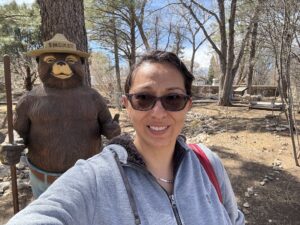 Figure taking a selfie in front of a statue of Smokey the Bear