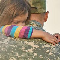 Little female child is hugging a soldier. Close up portrait of happy girl is hugging her father in military uniform.